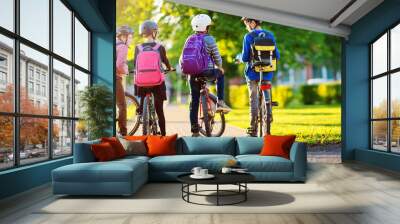 Children with rucksacks riding on bikes in the park near school Wall mural