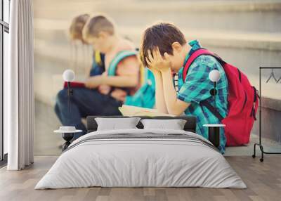 Children with rucksacks sitting on the stairs near school. Pupils with books and backpacks outdoors Wall mural