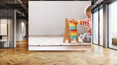 Cute child sitting on the floor in the room and playing with toys. Wall mural