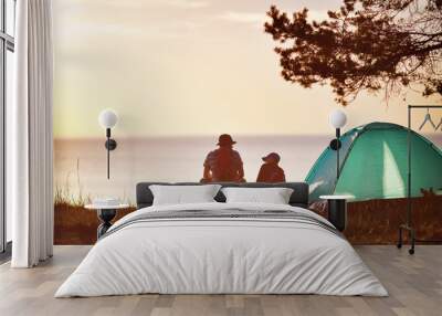 Family resting with tent in nature at sunset Wall mural