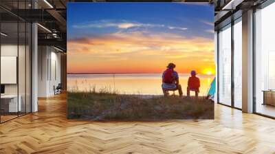 Family resting with tent in nature at sunset Wall mural