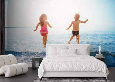 Happy children playing together in the sea in summer Wall mural