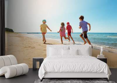 Happy kids on vacations at seaside running in the water Wall mural