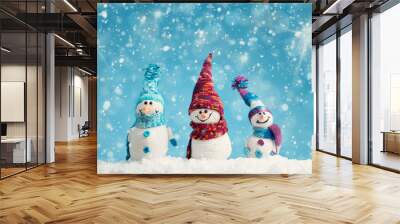 little knitted snowmans on soft snow on blue background Wall mural