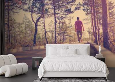 Man walking on wooden walkway in nature. Human silhouette in the morning Wall mural