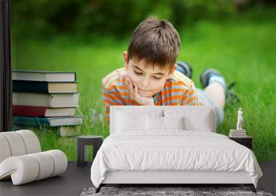 seven years old child reading a book lying on the grass Wall mural