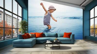 three years old boy playing at the beach in the water Wall mural