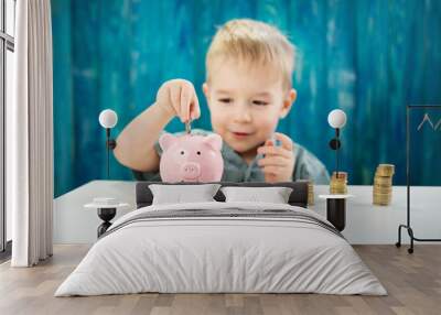 three years old child sitting st the table with money and a piggybank Wall mural