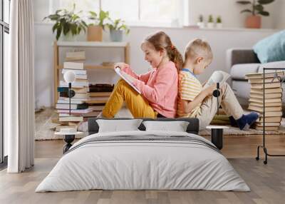 Two children sitting on the floor in the room and reading books Wall mural