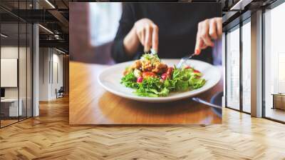 Woman eating a salad indoors in restaurant Wall mural