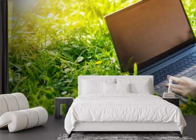 Woman lying with laptop on the blossoming meadow in natural park. Wall mural