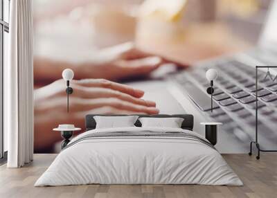 Woman with smartphone in her hand working on the laptop in office Wall mural