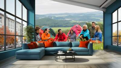 Sitting camping friends with tents and landscape Wall mural