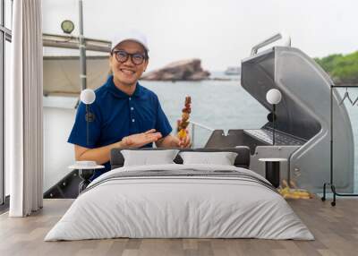 Asian man chef cooking grilled barbecue and seafood on stove for serving to passenger tourist travel on luxury private catamaran boat yacht on summer vacation. Cruise ship service occupation concept. Wall mural