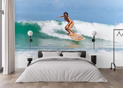 Asian woman surfer surfing and riding surfboard  the wave in the sea at tropical beach in sunny day. Healthy female enjoy outdoor activity lifestyle and water sport exercise surfing on summer vacation Wall mural