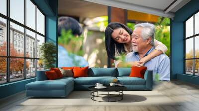 Asian woman surprise hugging elderly father from back at outdoor garden cafe restaurant on summer vacation. Family relationship, holiday celebrating, father's day and old people health care concept Wall mural