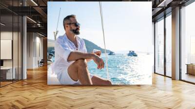 Caucasian man enjoy outdoor luxury lifestyle with alcoholic drinks while catamaran boat sailing at summer sunset. Handsome male relaxing outdoor leisure activity with tropical travel vacation trip Wall mural