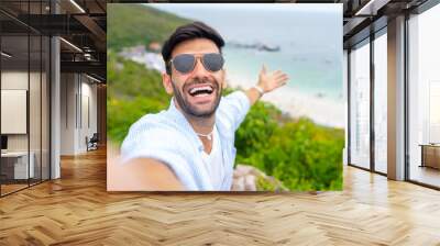 Caucasian man traveler using mobile phone taking selfie on mountain peak at tropical island in sunny day. Handsome guy enjoy outdoor lifestyle travel nature ocean on summer beach holiday vacation Wall mural