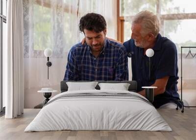 Caucasian senior father comforting and hugging depressed adult son in the bedroom. Elderly dad hugging and consoling crying son. Mental health, family relationship, healthcare and social issue concept Wall mural