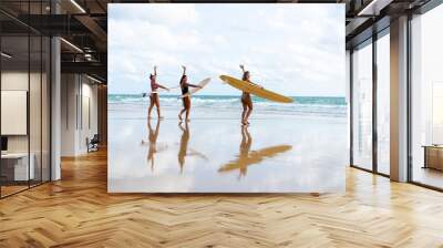 Group of Asian woman surfer in swimwear holding surfboard walking together on tropical beach at summer sunset. Female friends enjoy outdoor activity lifestyle water sport surfing on travel vacation Wall mural