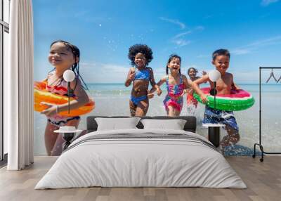 Group of Diversity little child boy and girl friends running and playing in sea water on tropical beach together on summer vacation. Happy children kid enjoy and fun outdoor lifestyle on beach holiday Wall mural