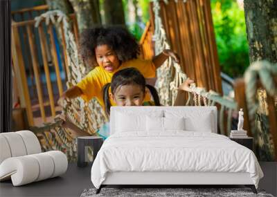 Group of Happy Little boy and girl friends playing and climbing rope net together at playground park on summer vacation. Children kid enjoy outdoor activity playing and learning at school playground Wall mural