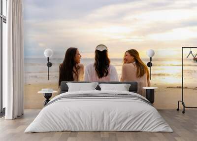 Group of Young Asian woman friends sitting and talking together on tropical island beach at summer sunset. Attractive girl enjoy and fun outdoor lifestyle travel on beach holiday vacation at the sea Wall mural