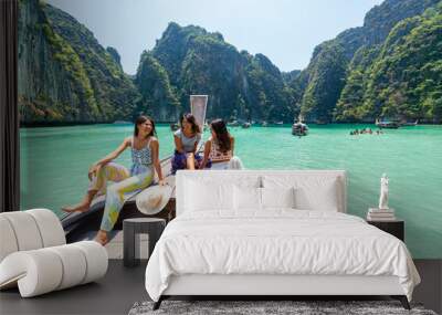 Group of Young Asian woman friends sitting on ship bow and looking beautiful nature of tropical island lagoon. Attractive girl relax and enjoy outdoor lifestyle travel on boat on summer beach vacation Wall mural