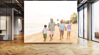 Happy Asian family travel ocean on summer holiday vacation. Grandparents and grandchildren boy and girl enjoy and fun outdoor lifestyle walking and playing together at tropical island beach at sunset. Wall mural