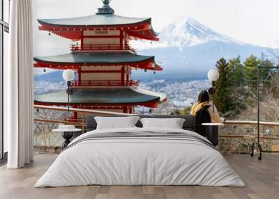 Happy Asian woman enjoy outdoor lifestyle travel at red Chureito Pagoda with Mt Fuji covered background in winter holiday vacation. People travel Japan landmark famous place and season change concept. Wall mural