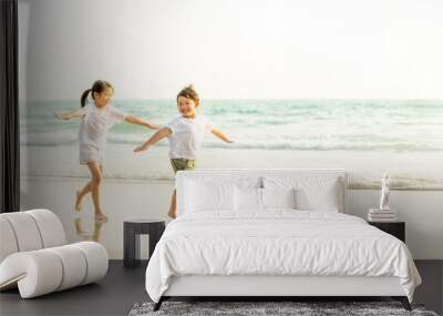 Happy little Asian brother and sister running and playing with smiling and laughing together on the beach at sunset. Adorable kids girl and boy relax and having fun in summer holiday vacation travel. Wall mural