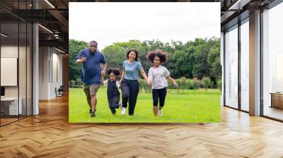 Happy mixed race family parents with cute child girl holding hands and running together in the park. Smiling father and mother with two daughter enjoy and having fun in summer outdoor holiday vacation Wall mural