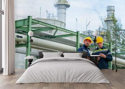 Male petrochemical engineers teamwork meeting discussion at petroleum oil refinery industry area. Industrial factory technician worker working maintenance inspect manufacturing energy power gas system Wall mural