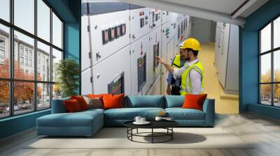 Professional electrical engineer in safety uniform working at factory server electric control panel room. Industrial technician worker maintenance checking power system at manufacturing plant room. Wall mural