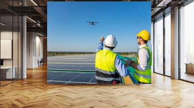 Professional engineer using drone and digital tablet maintaining solar cell panels together on building rooftop. Technician working on ecological solar farm. Renewable clean energy technology concept Wall mural