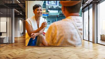 Two Asian drag queen gay friends in woman clothes meeting and drinking coffee together at coffee shop in the city. Diversity sexual equality, lgbtq pride people and transgender cross-dressing concept. Wall mural