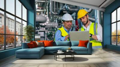 Two professional electrical engineer in safety uniform working together at factory site control room. Industrial technician worker maintenance power system at manufacturing industry plant room. Wall mural