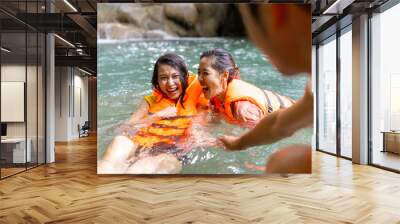 Young Asian man and woman enjoy and fun outdoor lifestyle travel nature forest mountain on summer holiday vacation. Happy people friends in vest life relaxing and playing water together at waterfall. Wall mural