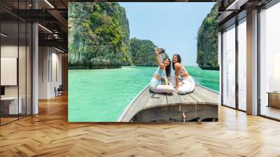 Young Asian woman friends using mobile phone taking selfie together while travel on boat passing island beach lagoon in sunny day. Happy female enjoy and fun outdoor lifestyle on summer vacation trip Wall mural