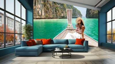 Young beautiful Asian woman in blue dress sitting on the boat passing island beach lagoon in summer sunny day. Happy female relax and enjoy outdoor lifestyle together on summer vacation in Thailand Wall mural