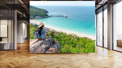 Young beautiful Asian woman with backpack solo travel on tropical island mountain peak in summer sunny day. Cheerful female relax and enjoy outdoor lifestyle in summer beach holiday vacation trip Wall mural