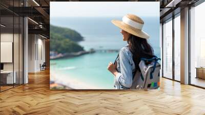 Young beautiful Asian woman with backpack solo travel on tropical island mountain peak in summer sunny day. Cheerful female relax and enjoy outdoor lifestyle in summer beach holiday vacation trip Wall mural