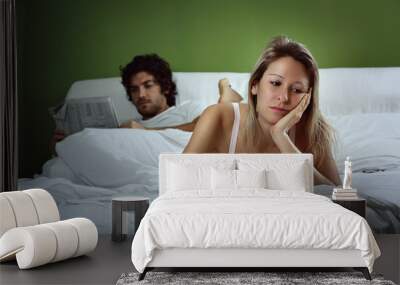 Woman in bed with unhappy expression Wall mural