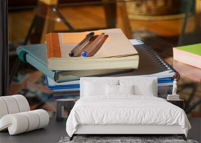 Neat and organized scene: Notebooks arranged on a glass table, accompanied by a pencil, creating a simple yet inviting workspace. Wall mural