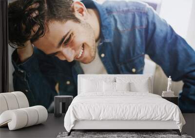 fashionable young man smiling with his hand on his hair, portraits Wall mural