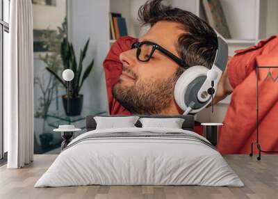 relaxed man at home listening to music with headphones Wall mural