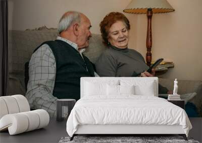 senior couple at home with phone and book on sofa Wall mural