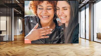 smiling girls looking at mobile phone in the street Wall mural