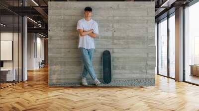 teen boy with skateboard on wall with copy space Wall mural