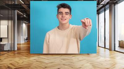 teenager boy pointing isolated on background Wall mural